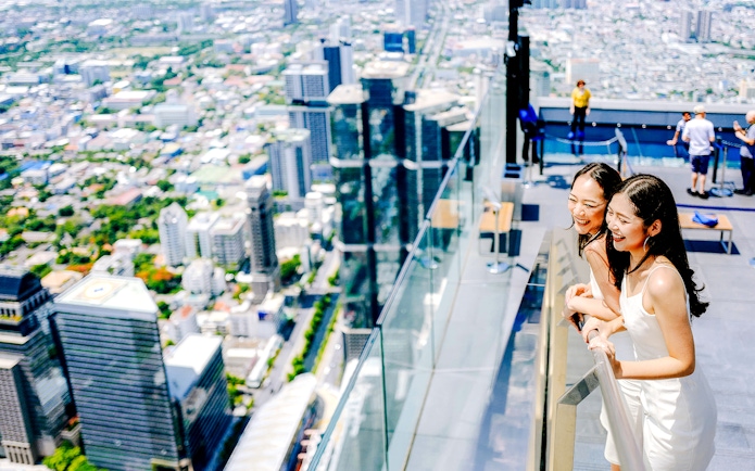 Friends enjoying the view from Mahanakhon SkyWalk in Bangkok, Thailand.