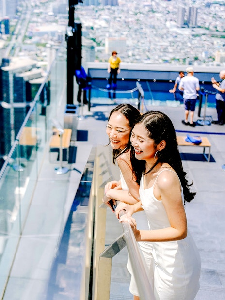 Friends enjoying the view from Mahanakhon SkyWalk in Bangkok, Thailand.
