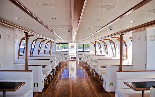 Interior of a deluxe boat for La Maddalena Archipelago tour with seating and large windows.