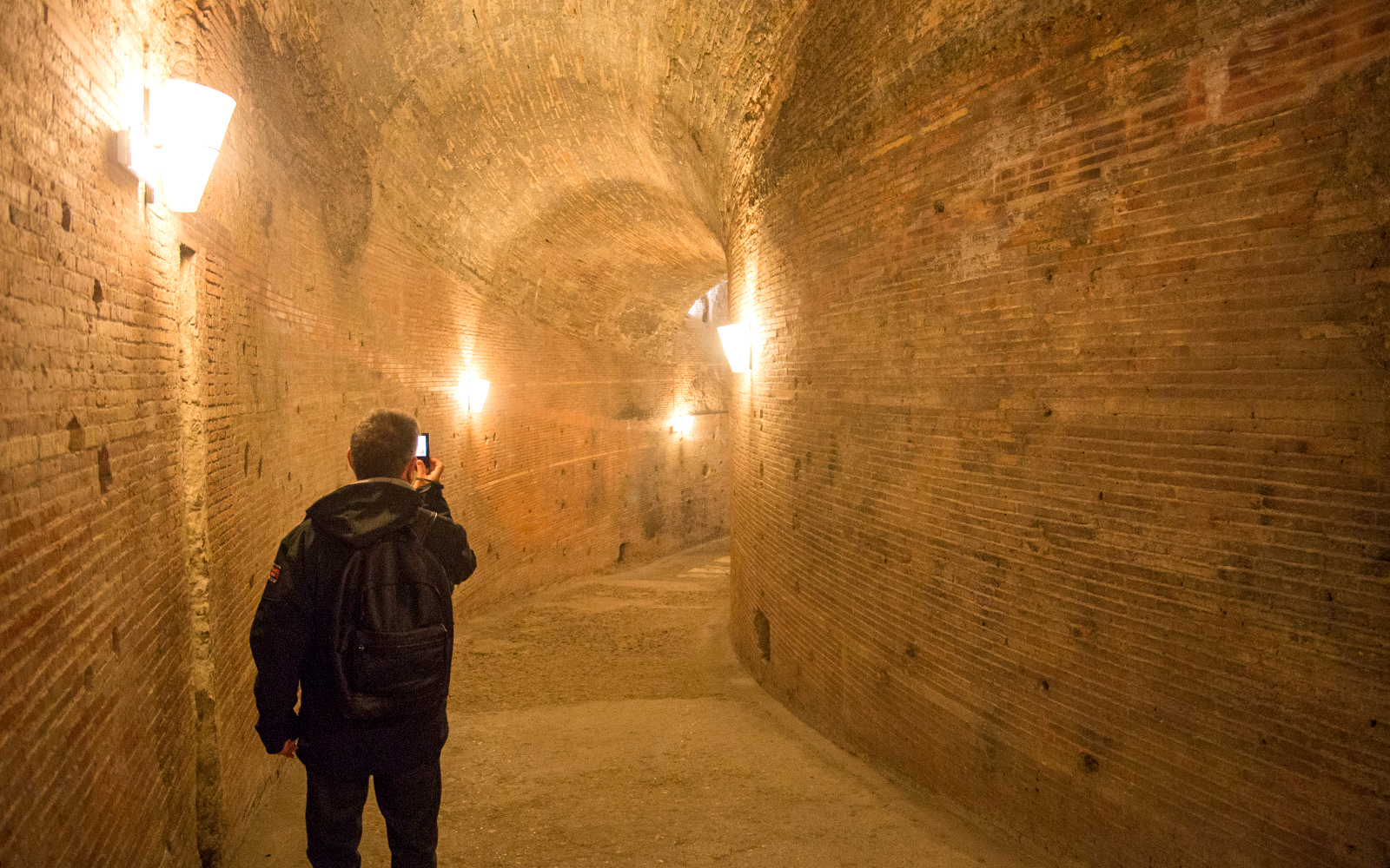 Visitor exploring a brick corridor inside Castel Sant'Angelo, Rome.