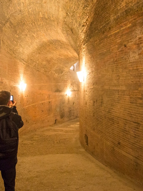 Visitor exploring a brick corridor inside Castel Sant'Angelo, Rome.