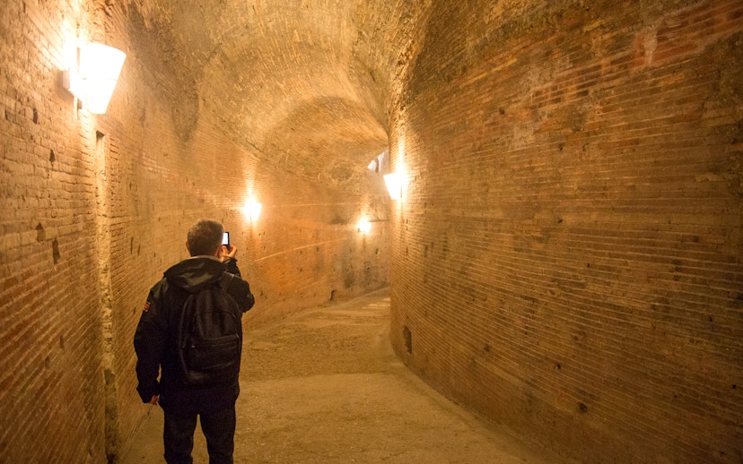 Visitor exploring a brick corridor inside Castel Sant'Angelo, Rome.