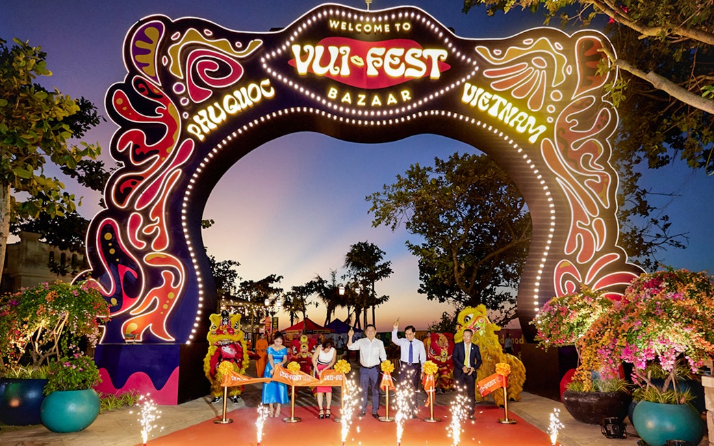 Tourists at Vui Fest Bazaar entrance on Phu Quoc Island, Vietnam, with cultural performances.