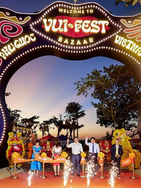 Tourists at Vui Fest Bazaar entrance on Phu Quoc Island, Vietnam, with cultural performances.