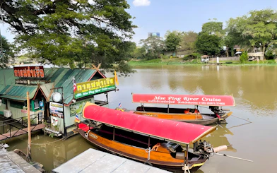 Mae Ping River Cruise boats docked by a riverside cafe in Chiang Mai.