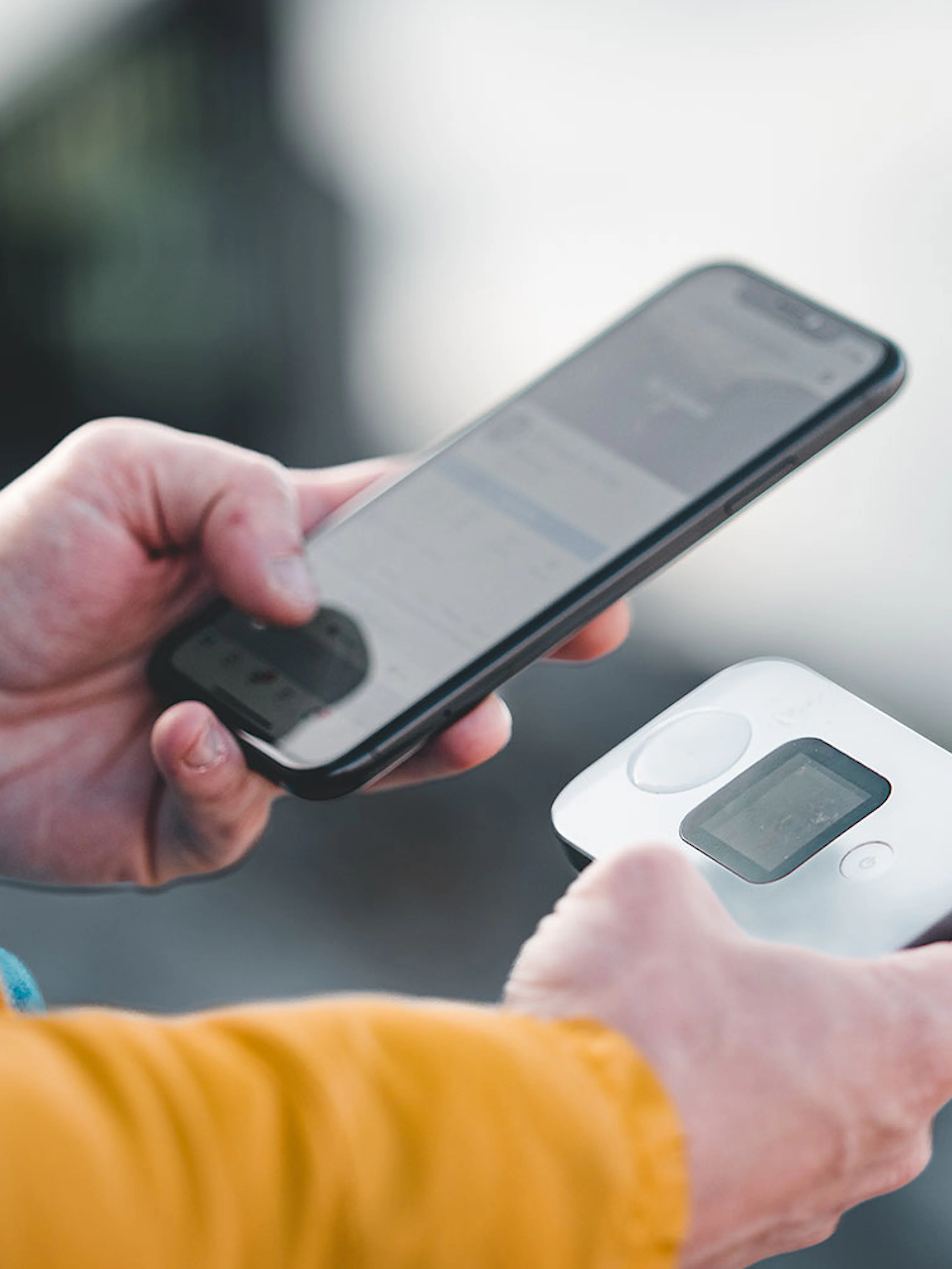 Hands holding a smartphone and a portable 4G Wi-Fi router.