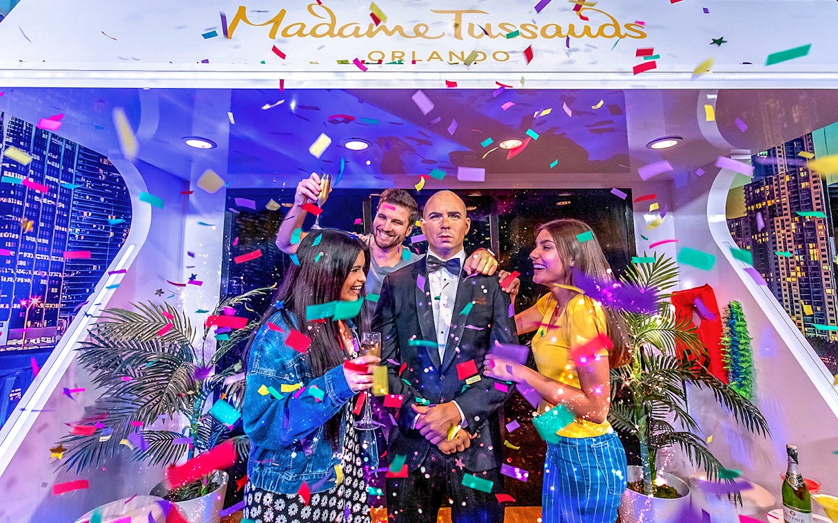 Tourists celebrating with Pit Bull wax statue at Madame Tussauds Orlando.