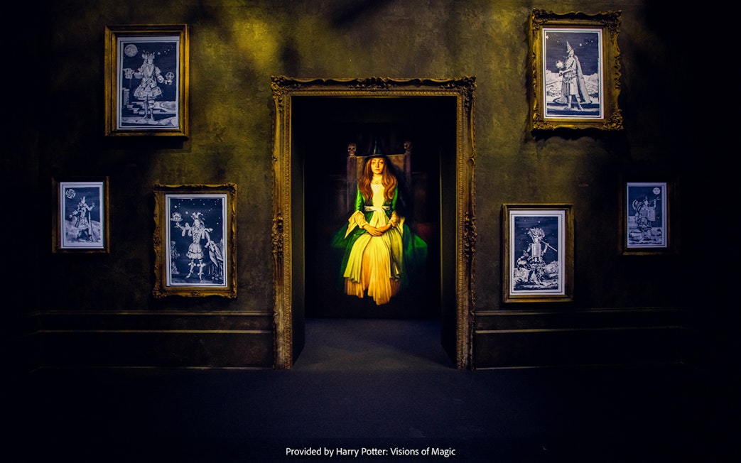 Framed magical portraits in a dimly lit room at Harry Potter: Visions of Magic exhibit.