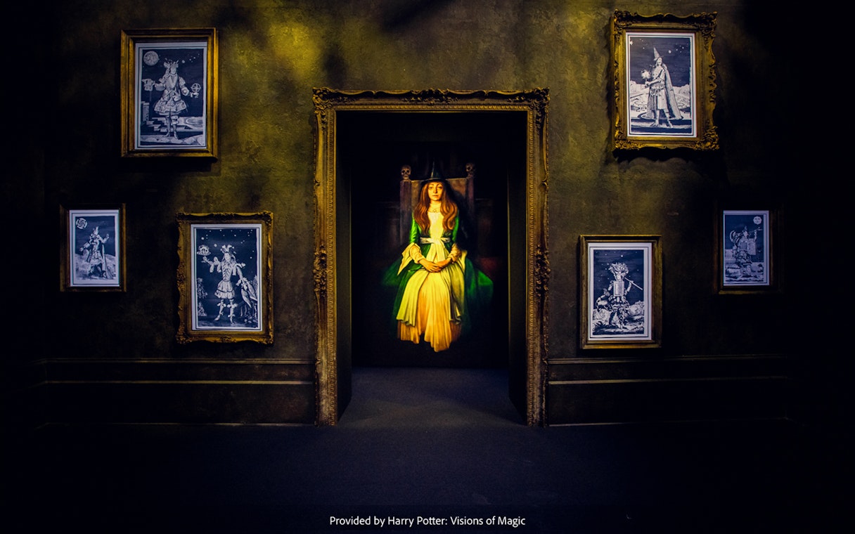 Framed magical portraits in a dimly lit room at Harry Potter: Visions of Magic exhibit.