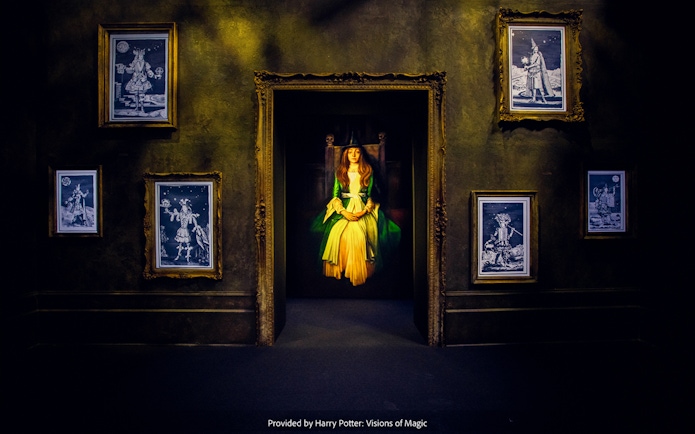 Framed magical portraits in a dimly lit room at Harry Potter: Visions of Magic exhibit.