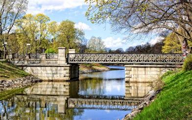 Djurgården Bridge over calm water surrounded by trees in Stockholm, Sweden.