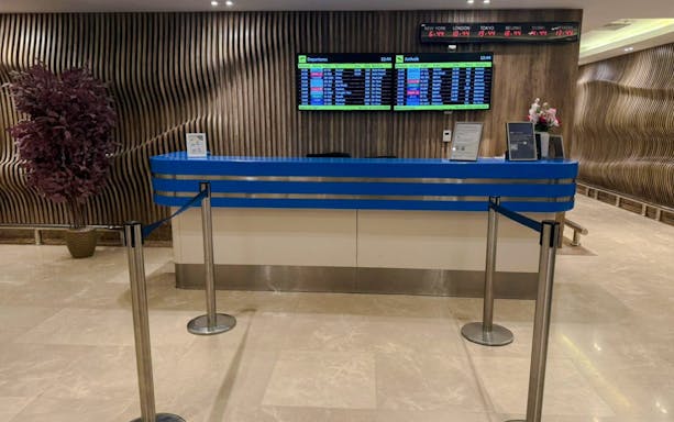 Reception desk at Plaza Premium Lounge, Cairo with flight information screens.