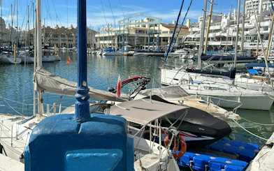 Benalmádena marina with sailboats and waterfront buildings, part of the Don Quixote city exploration game.