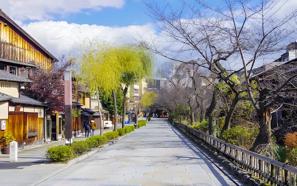 Gion street with traditional wooden buildings and trees in Kyoto, Japan.