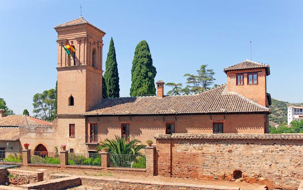 Alhambra's Torre de la Vela with surrounding gardens in Granada, Spain.