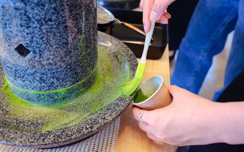 Grinding tencha leaves into matcha powder with a granite stone mill in Japan.