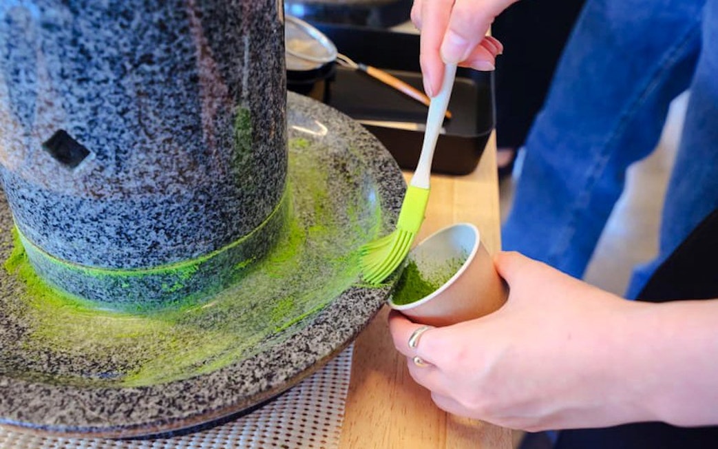 Grinding tencha leaves into matcha powder with a granite stone mill in Japan.