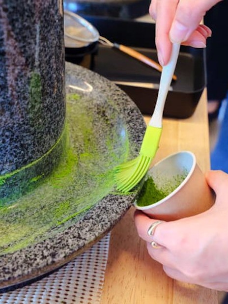Grinding tencha leaves into matcha powder with a granite stone mill in Japan.