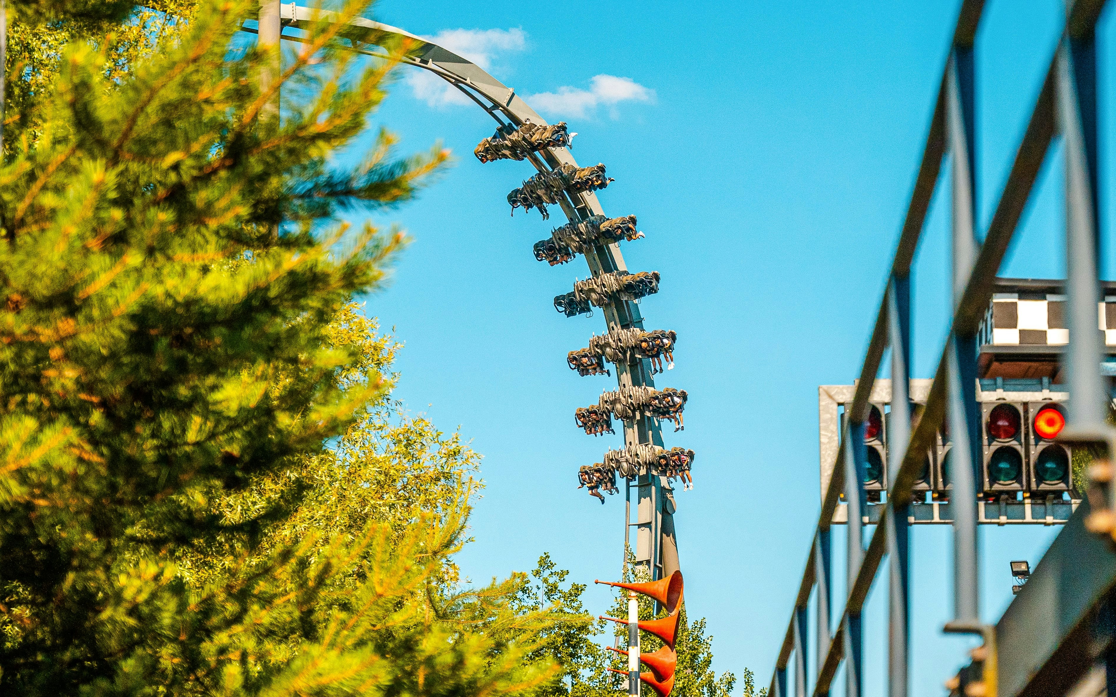 Roller coaster loop on The Swarm ride at Thorpe Park, London, with trees and track in view.