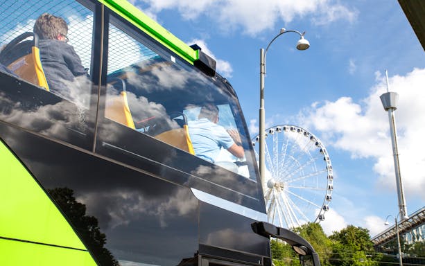 Hop on hop off bus in Gothenburg passing by a Ferris wheel.