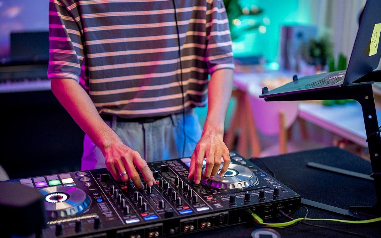 DJ mixing music on a controller in a vibrant studio setting.