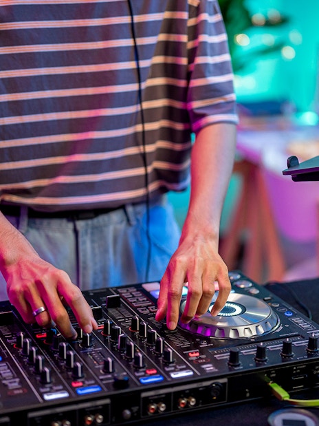 DJ mixing music on a controller in a vibrant studio setting.