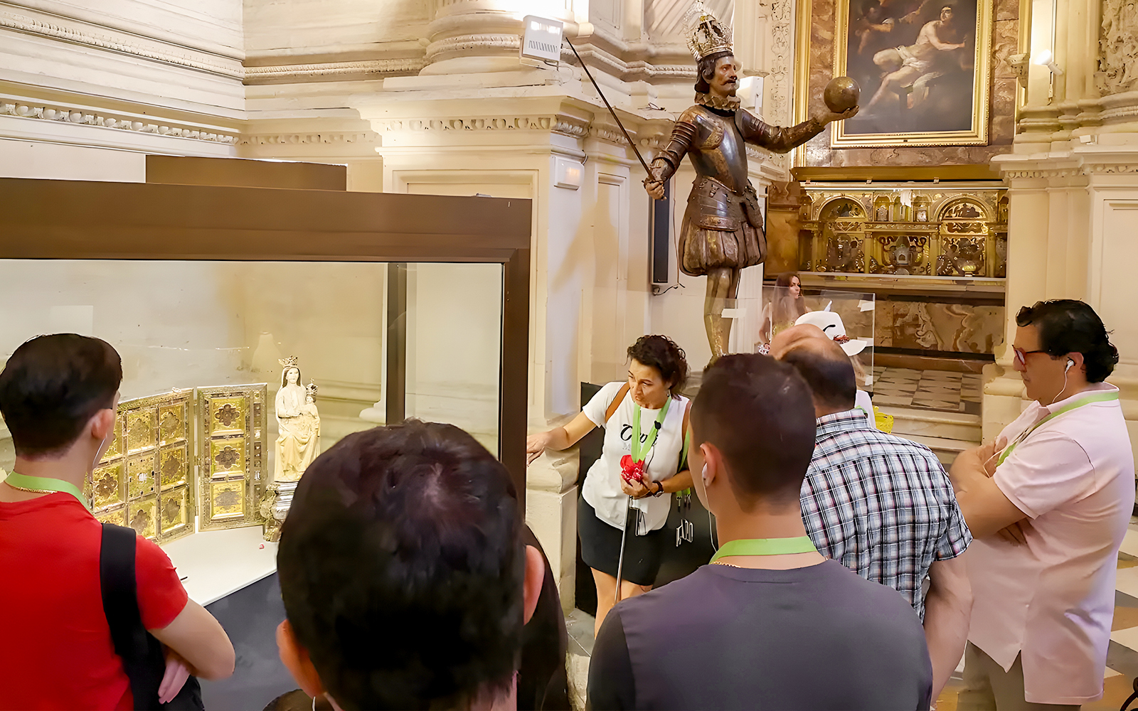 Tourists with guide viewing Seville Cathedral exhibit featuring religious artifacts.