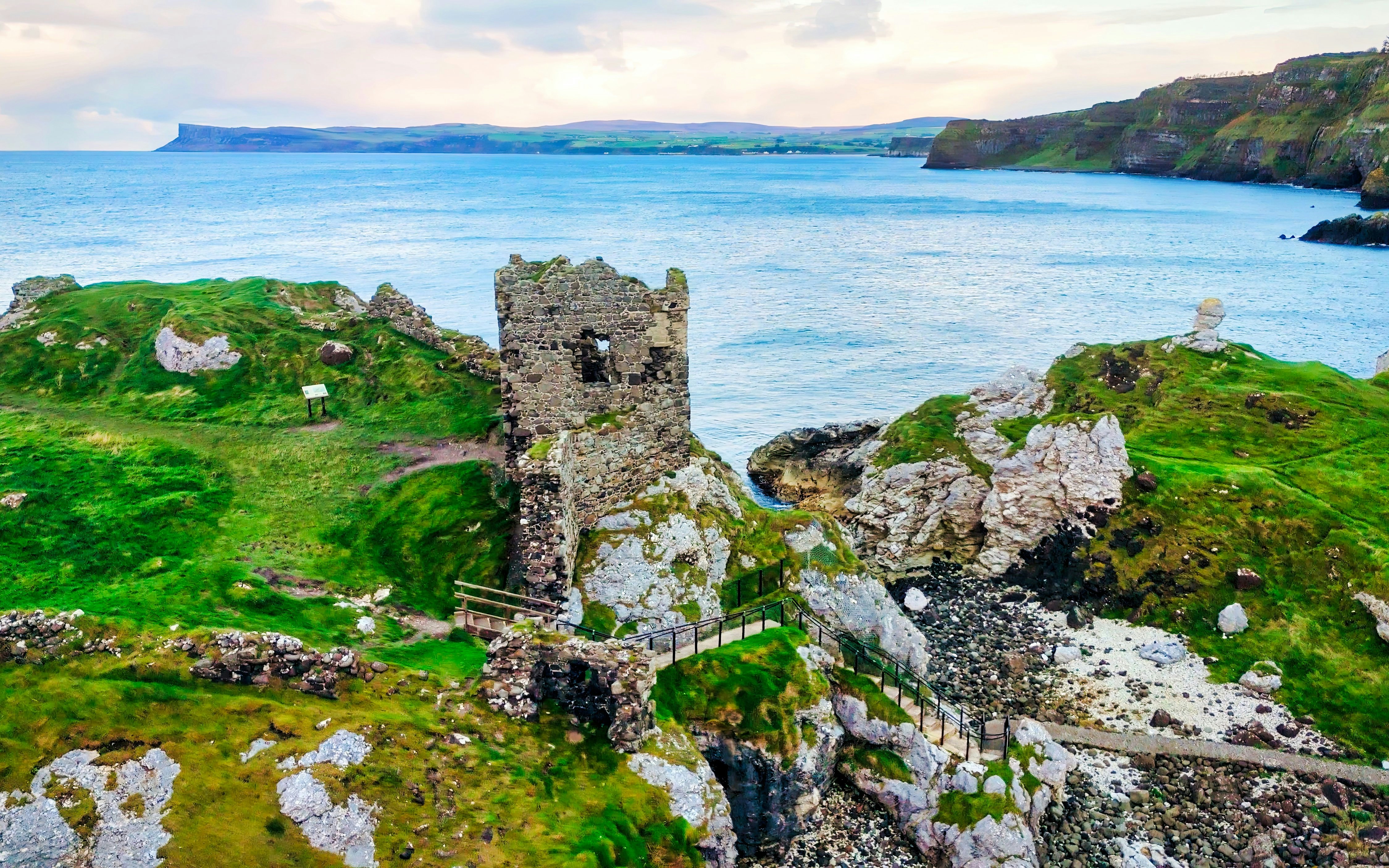 Kinbane Castle ruins on a coastal cliff in Northern Ireland with ocean backdrop.