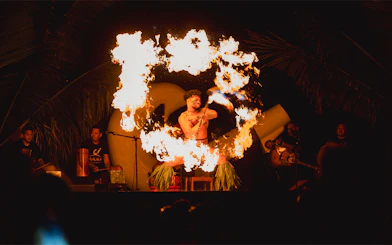 Fire dancer performing at Mauka Warriors Luau with flaming torches.