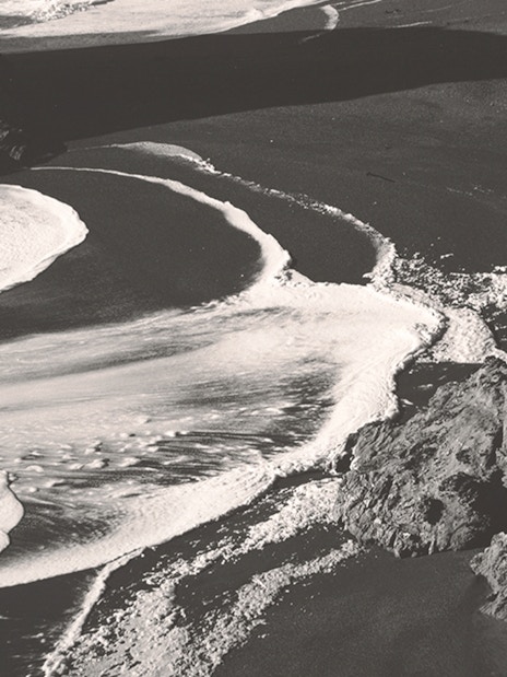 Black and white photograph of ocean waves on a rocky shore, part of an exhibit at Fundación MAPFRE Madrid.