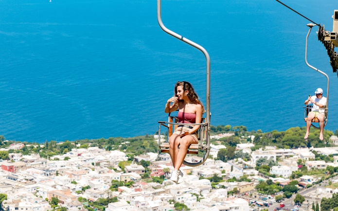 Tourist enjoying Monte Solaro Chair Lift with view of Anacapri, Italy.