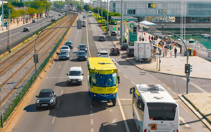 HIPPOtrip vehicle driving on a city road alongside cars and a tram line.