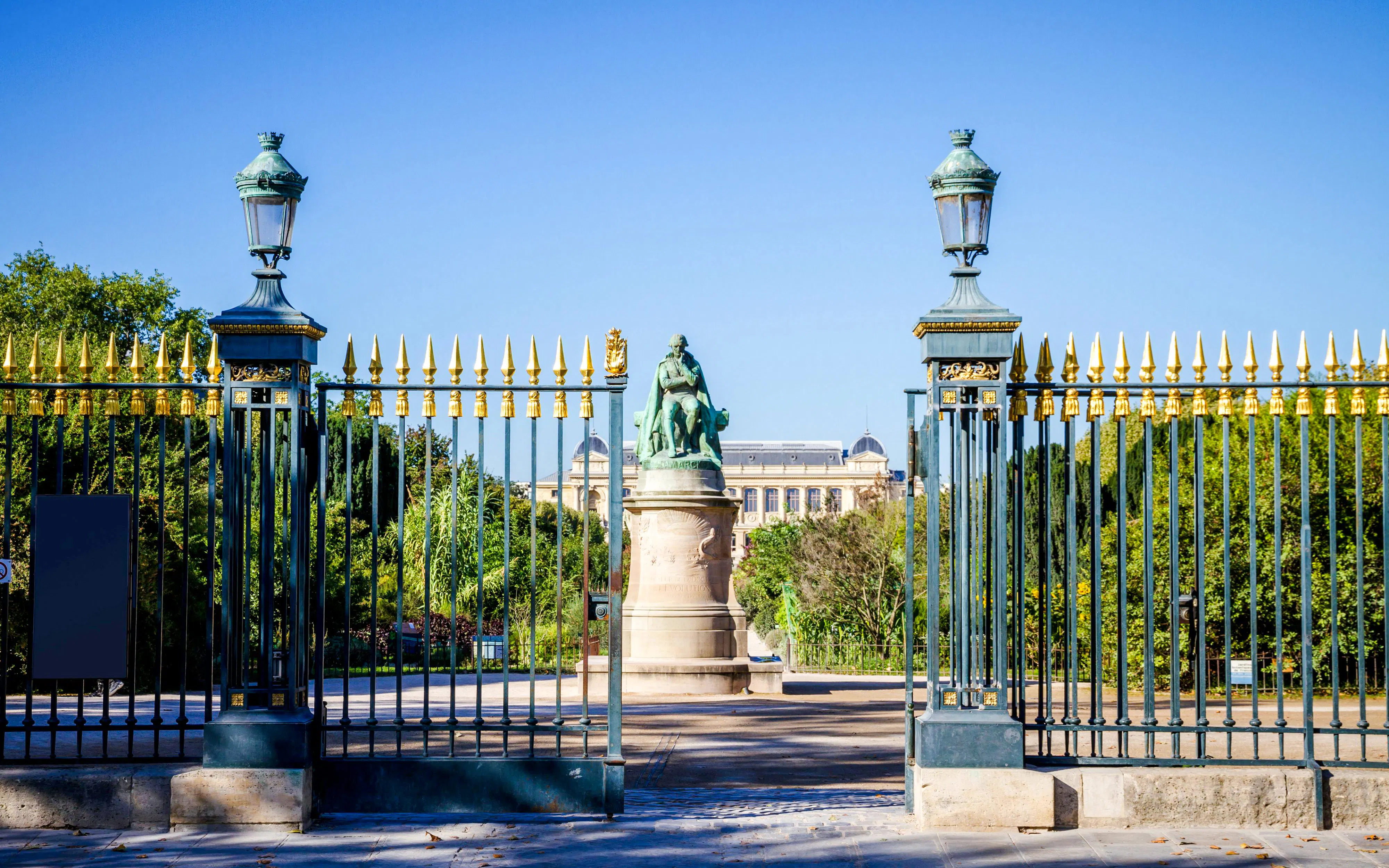 Entrance gate to Garden of Plants Park with statue and greenery, Paris, France.