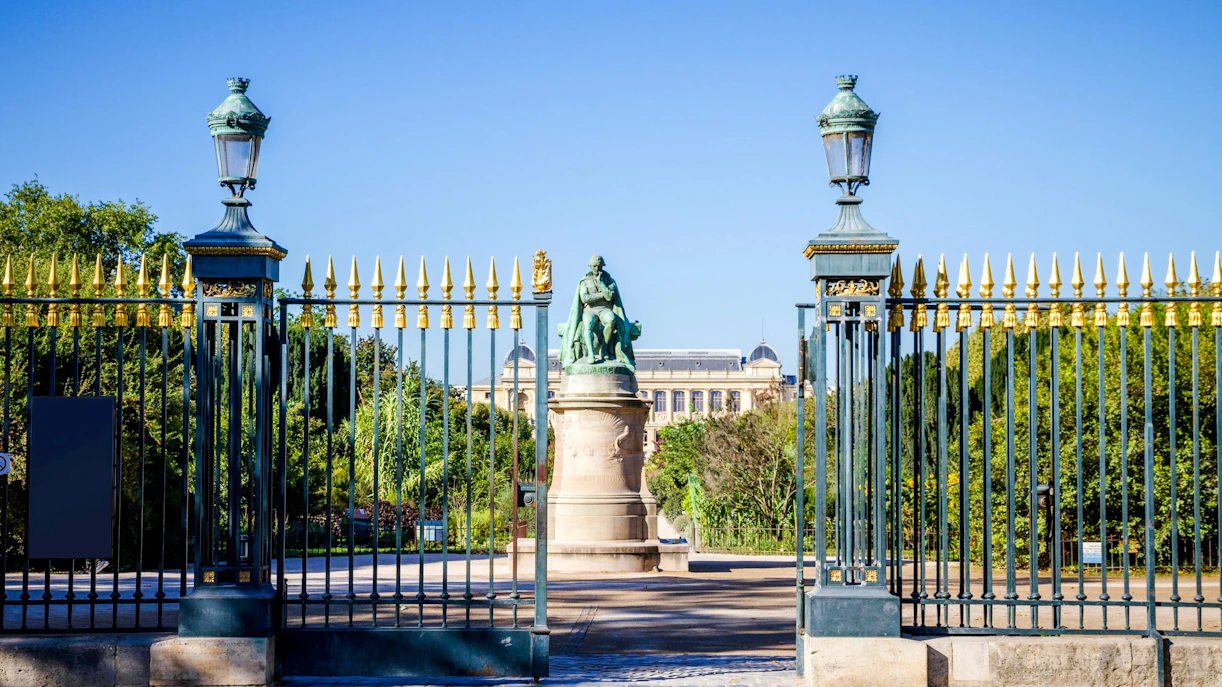 Entrance gate to Garden of Plants Park with statue and greenery, Paris, France.