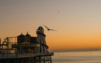 Brighton Pier at sunset with seagulls flying, part of the Gone With the Tide city exploration game.