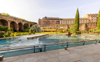 Outdoor pool and garden area at QC Terme spa in Milan with historic architecture.