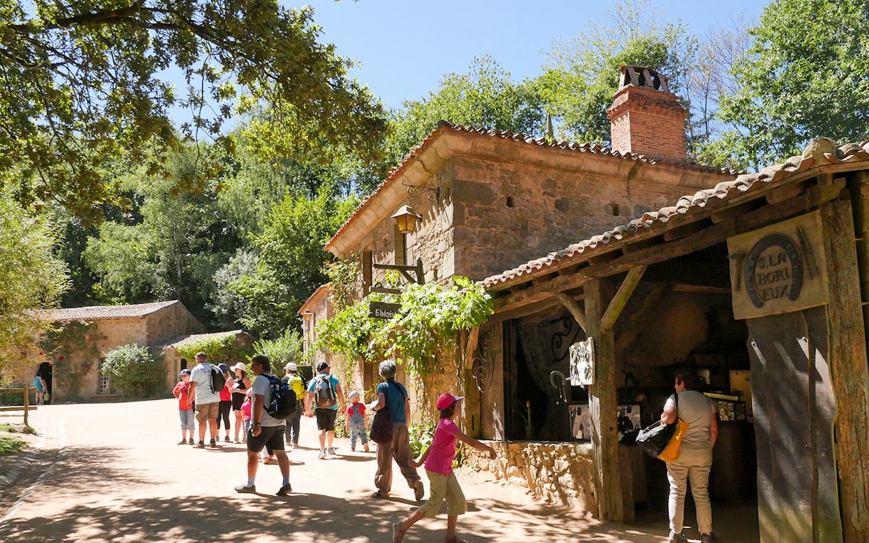 Visitors exploring rustic village at Puy du Fou Theme Park.