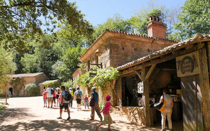 Visitors exploring rustic village at Puy du Fou Theme Park.