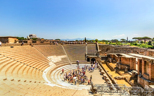Pompeii amphitheater with tourists exploring, featuring augmented reality experience.
