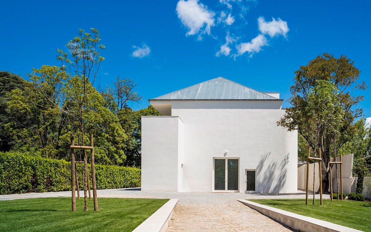 Modern white building at Serralves, Porto, surrounded by trees and a clear blue sky.