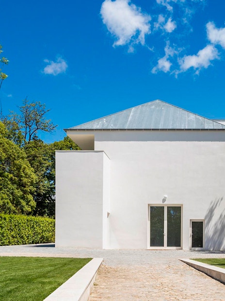 Modern white building at Serralves, Porto, surrounded by trees and a clear blue sky.