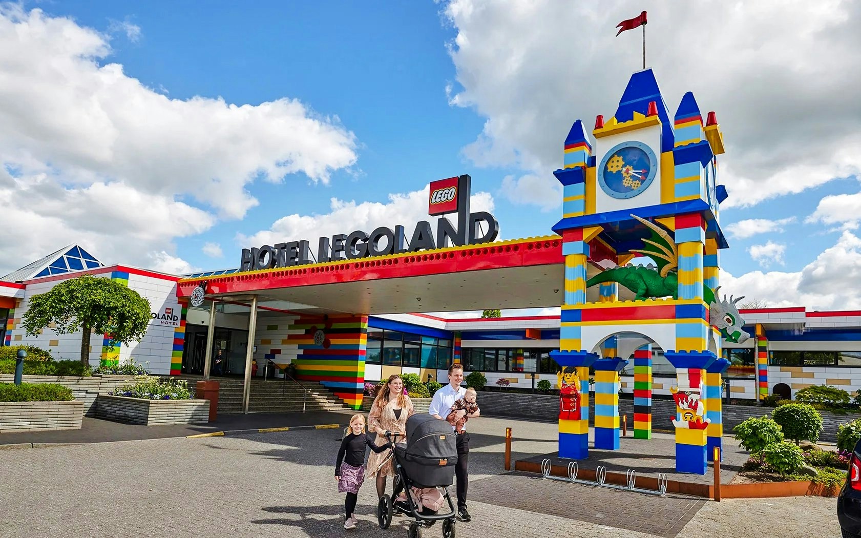 Family outside Hotel LEGOLAND entrance with colorful LEGO-themed architecture in Billund.