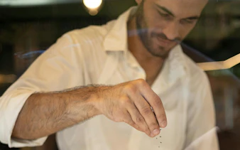 Man sprinkling herbs during Athens food tour tasting experience.