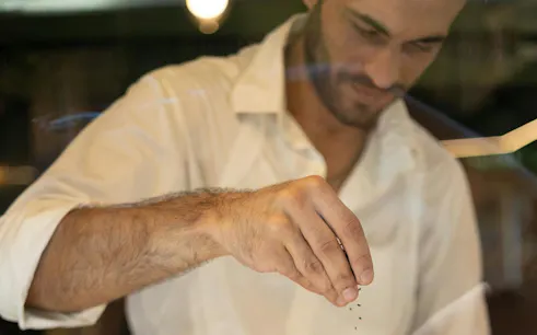 Man sprinkling herbs during Athens food tour tasting experience.