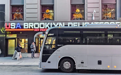 Bus parked in front of Brooklyn deli with Christmas lights, New York.
