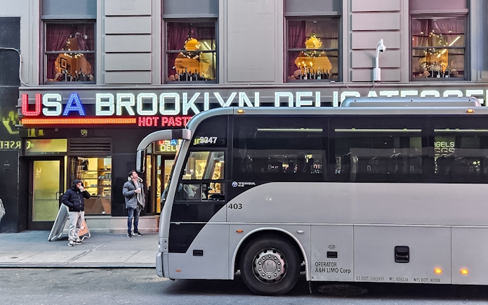 Bus parked in front of Brooklyn deli with Christmas lights, New York.