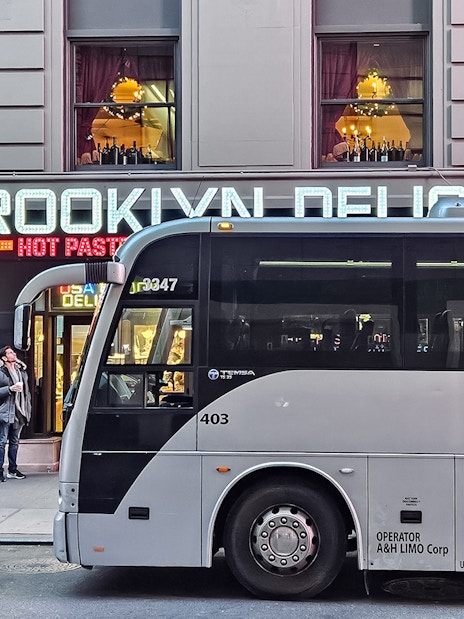 Bus parked in front of Brooklyn deli with Christmas lights, New York.