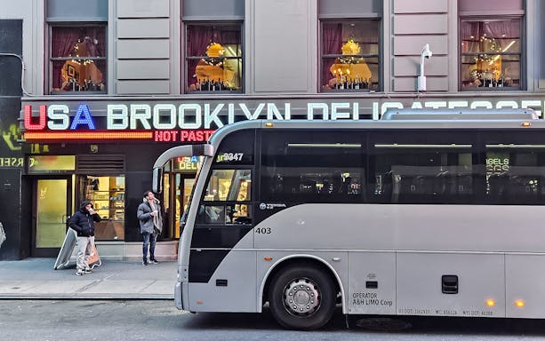 Bus parked in front of Brooklyn deli with Christmas lights, New York.