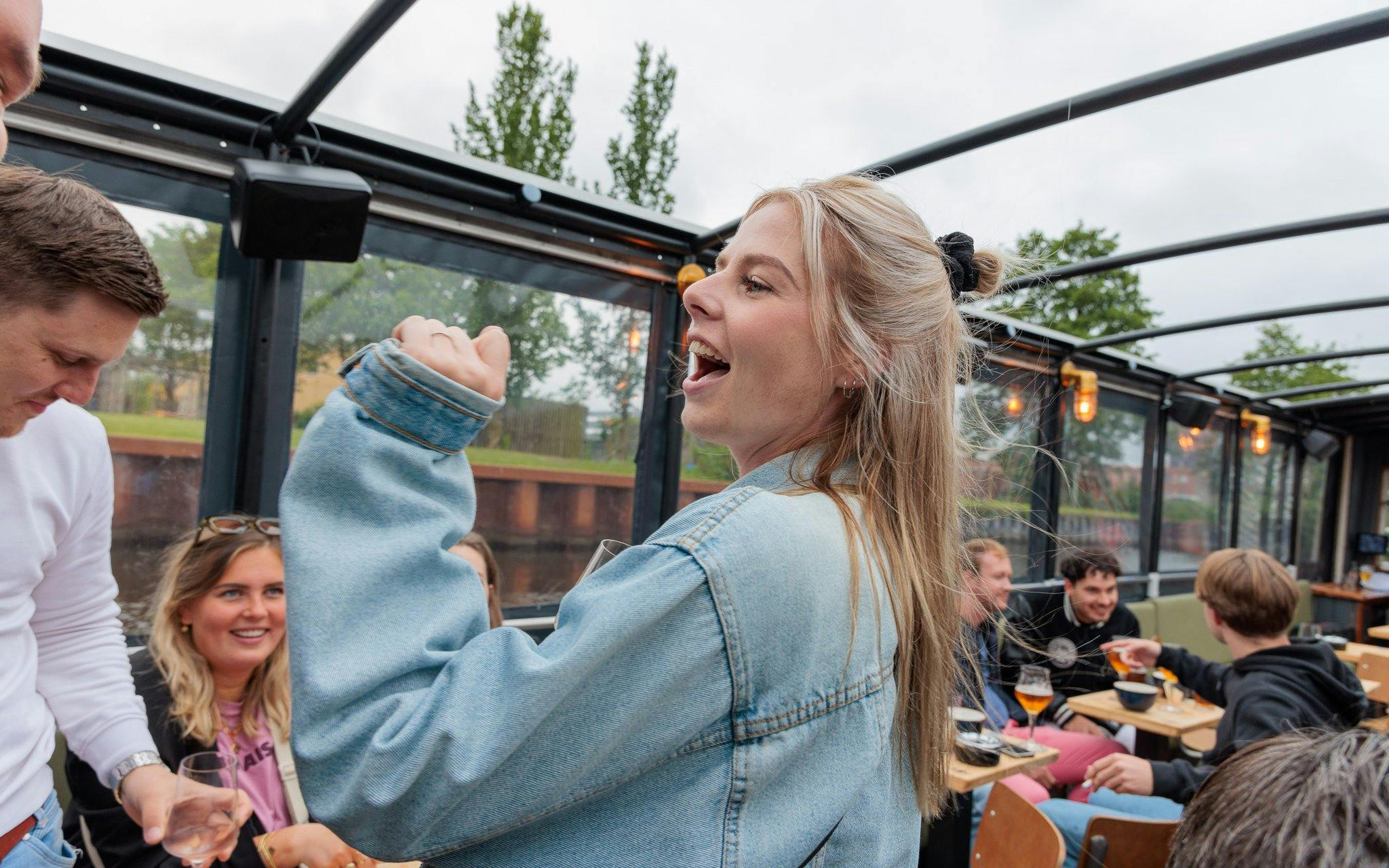 Group enjoying drinks on a terrace boat in Groningen with a cozy bar atmosphere.