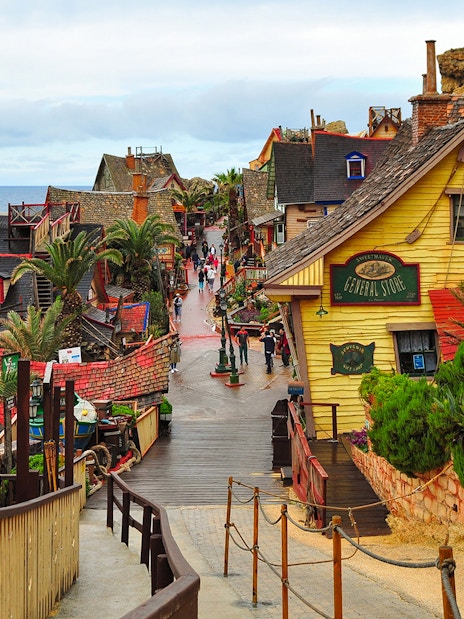 Street view of colorful wooden buildings in Popeye Village, Malta, near the sea.